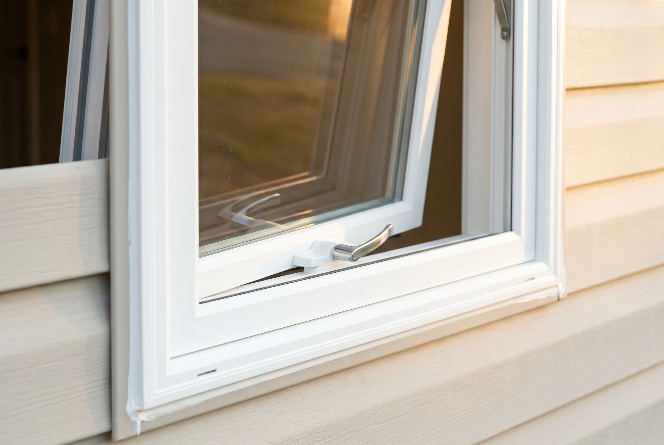 Brand-new MI vinyl casement window cranked open about 30 degrees, crank handle visible, clean white frame